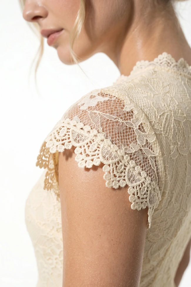 Elegant champagne floral lace pleated A-line maxi dress by FJØRNA, perfect for wedding guest attire, shown in close-up detail.