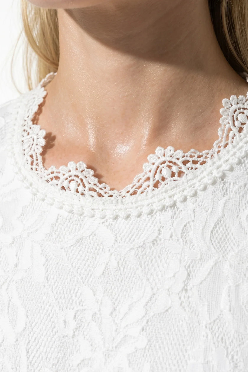 Elegant white floral lace pleated A-line maxi dress by FJØRNA, perfect for wedding guests, shown in a close-up view.