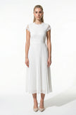 White floral lace pleated A-line maxi dress by FJØRNA, elegant wedding guest dress with flowing fabric and intricate lace details.
