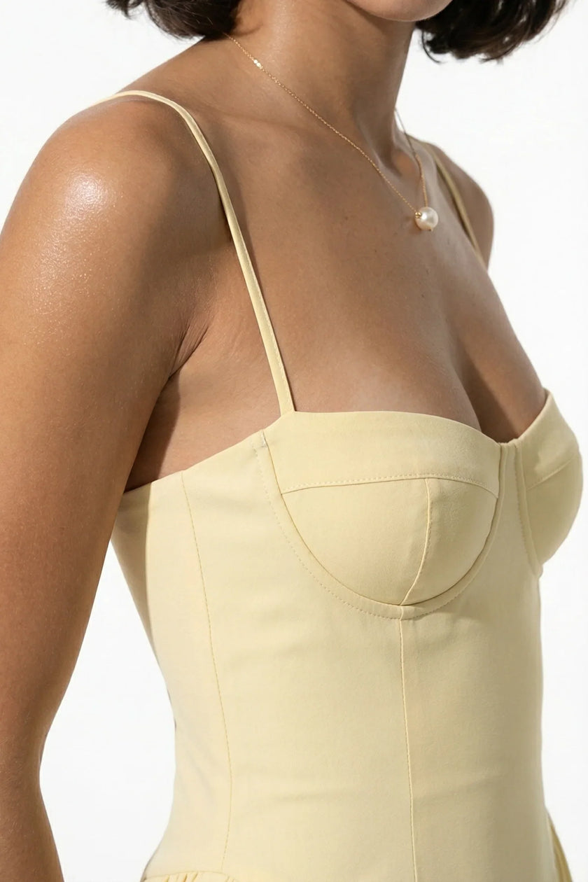 FJØRNA butter yellow sleeveless pleated halter backless midi dress for women, elegant occasion dress on a model.