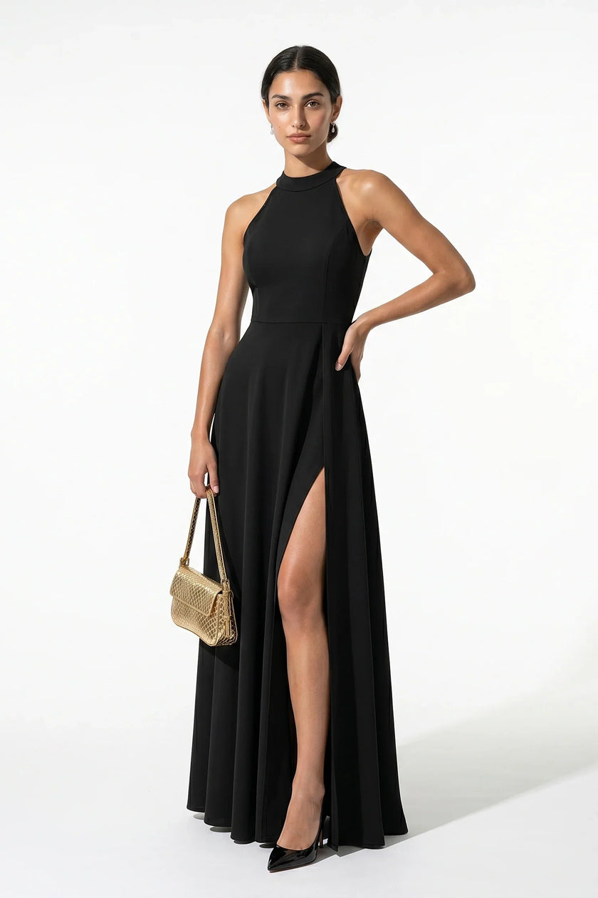 Black FJØRNA sleeveless maxi dress with high neck, A-line silhouette, and side slit, shown full-body on a woman.