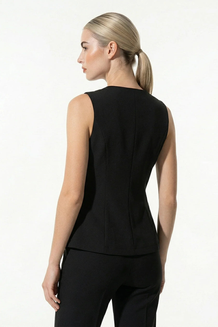 Black women's sleeveless waistcoat with metal buttons, FJØRNA tailored layering piece, close-up detail shot.