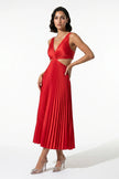 Red FJØRNA pleated V-neck maxi dress with cut-out waist, featuring suspender straps and full-length flowing design.