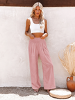 FJØRNA linen summer trousers for women, wide-leg palazzo style, with a flowy fit and light, breathable fabric in soft neutral tones.