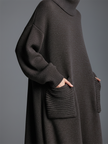 Brown knit maxi dress for women by FJØRNA, featuring a flowing design and long sleeves, displayed on a model.