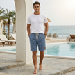 FJØRNA men's casual drawstring shorts with pockets and elegant accents, shown in a relaxed lifestyle setting.