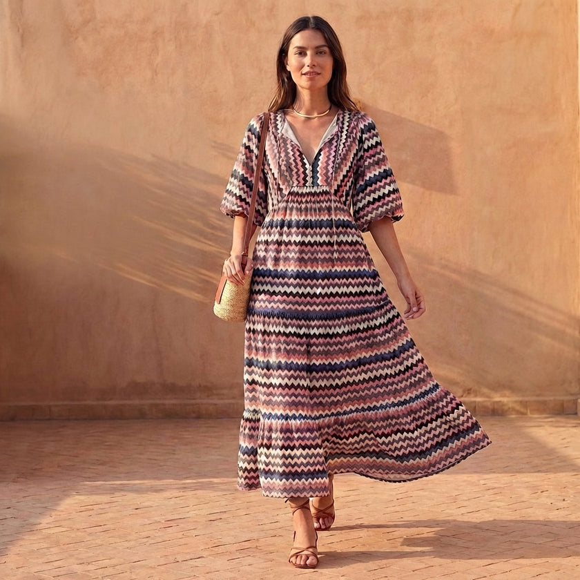 FJØRNA elegant women's maxi dress with V-neck and puff sleeves, shown in a stylish lifestyle setting.