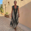 FJØRNA elegant women's maxi dress with geometric V-neck, flowing fabric, worn by a model in a stylish outdoor setting.