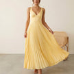 Women’s elegant V-neck sleeveless maxi dress by FJØRNA, featuring pleated design, worn by a model in a fashion photoshoot.