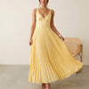 Women’s elegant V-neck sleeveless maxi dress by FJØRNA, featuring pleated design, worn by a model in a fashion photoshoot.