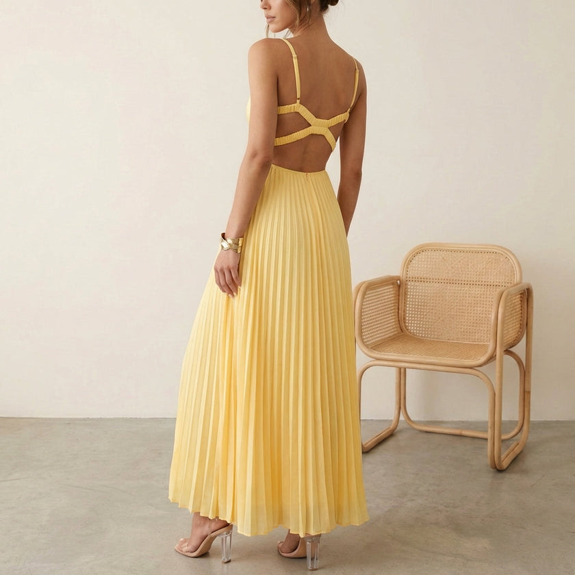 Model wearing FJØRNA elegant sleeveless maxi dress with V-neck and pleated design, showcasing flowing fabric and sophisticated style.