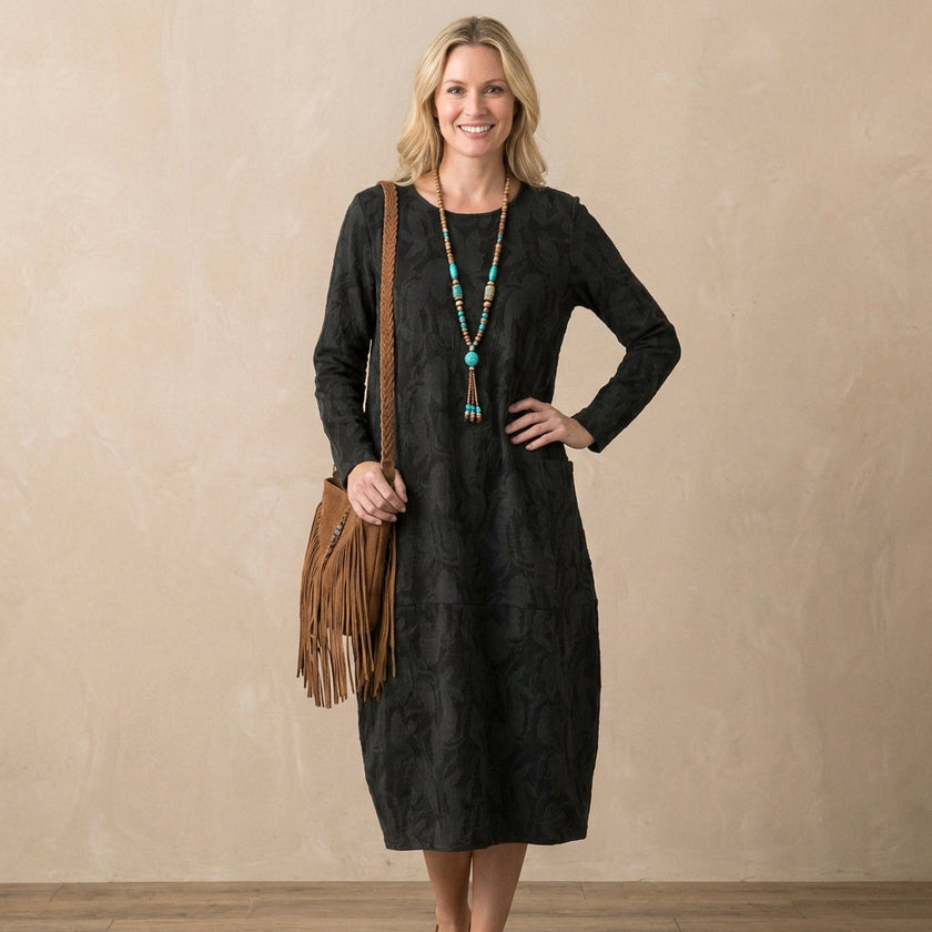 FJØRNA elegant women's maxi dress with long sleeves and pockets, modeled on woman showcasing flowy fabric and stylish design.