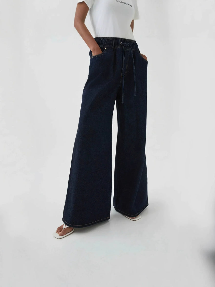 Blue denim wide-leg drawstring jeans for women by FJØRNA, relaxed fit pants with a comfortable waistband and casual style.