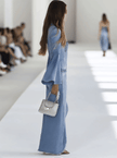 Light blue denim flared long sleeve jumpsuit by FJØRNA featuring wide-leg pants and a fitted bodice with button details.