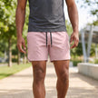 Men's pink FJØRNA woven athletic shorts with adjustable waist and side pockets, designed for active wear and comfort.