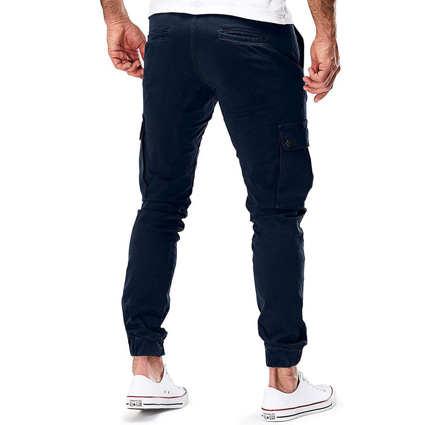 FJØRNA men's durable cargo pants with multiple pockets, suitable for outdoor and urban wear, shown in a rugged outdoor setting