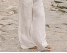 FJØRNA linen wide-leg pull-on trousers for women, loose fit, natural beige color, shown on a woman modeling relaxed casual style.