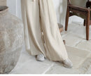 Light beige linen wide-leg trousers for women by FJØRNA, featuring loose pull-on style and relaxed fit.