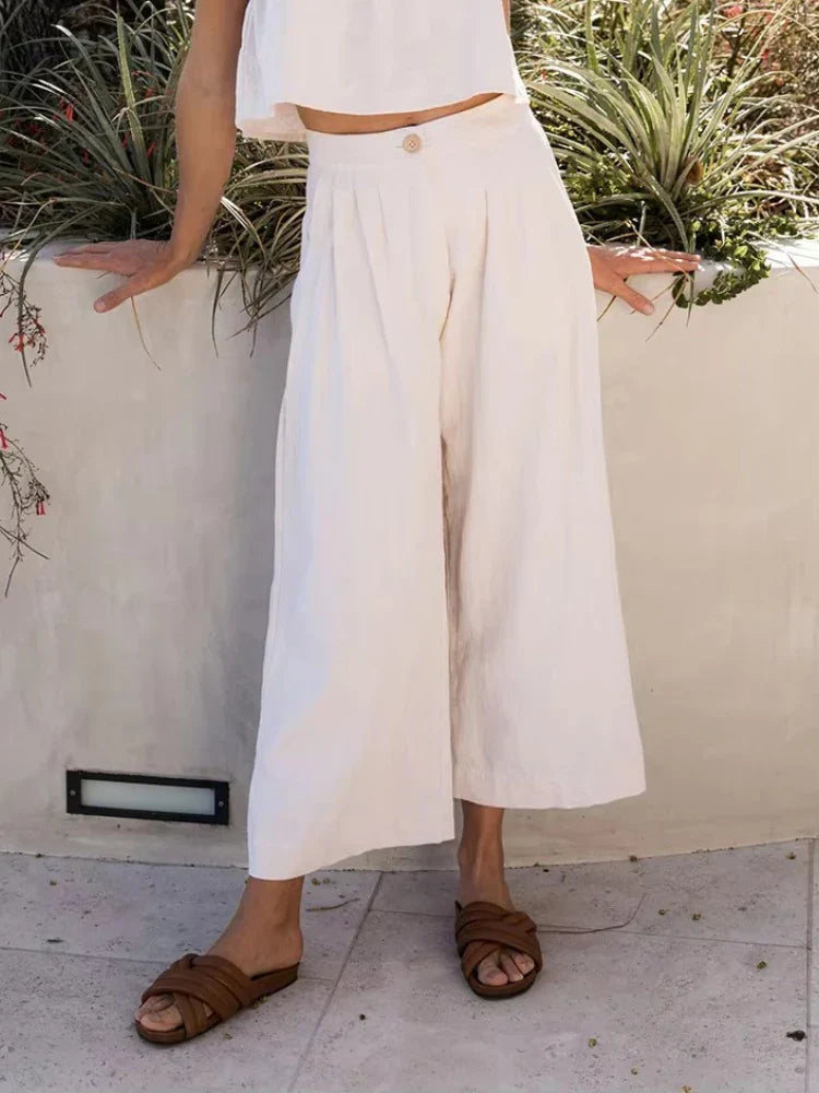 FJØRNA women's linen cropped culotte trousers with wide-leg design, soft beige fabric, and relaxed fit.