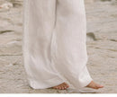 FJØRNA linen wide-leg trousers for women, loose pull-on pants with relaxed fit and natural linen fabric, shown in a neutral color.