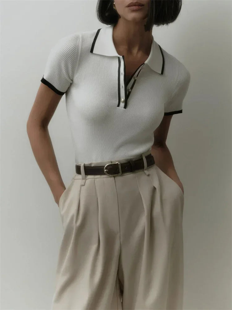 Black cotton polo top for women by FJØRNA, featuring a classic polo shirt design with a collar and short sleeves.