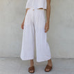 FJØRNA women's linen cropped culotte trousers with wide-leg design, lightweight natural fabric, and relaxed fit.