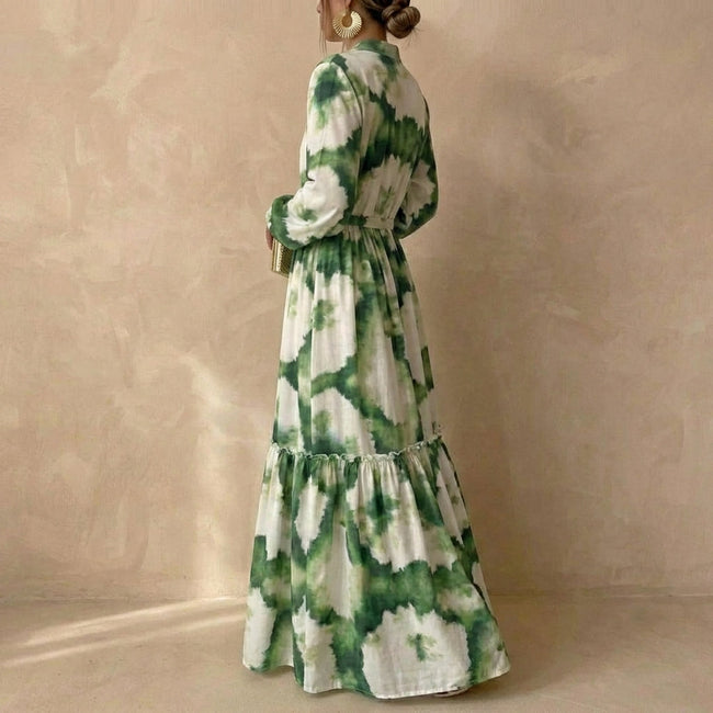FJØRNA A-line maxi dress with V-neck and puff sleeves shown from side view, flowing fabric and elegant silhouette.