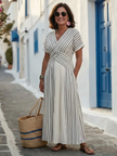 Flowy summer midi dress for women by FJØRNA, featuring short sleeves and a wrap design, shown in a vibrant floral pattern.