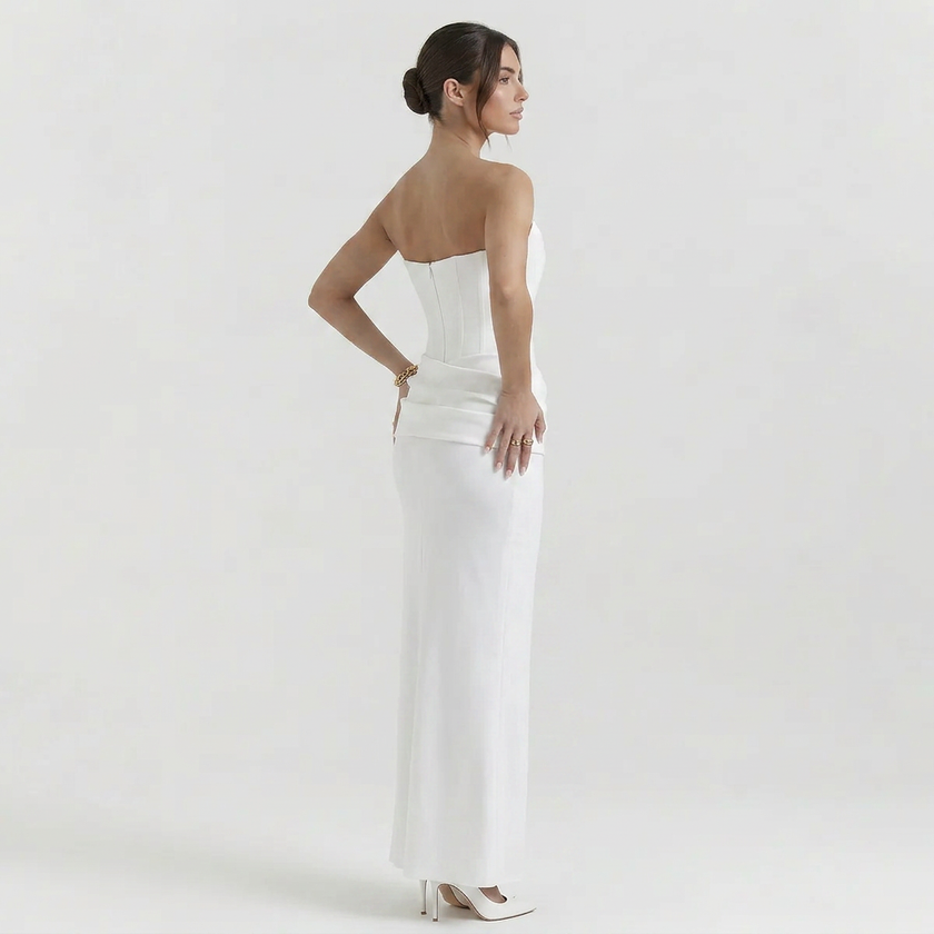 Side profile of a white women's strapless corset maxi dress by FJØRNA, featuring a fitted bodice and flowing skirt.