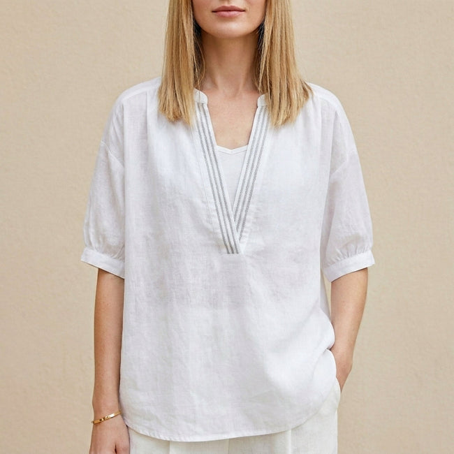 White women's summer blouse with V-neck and puff sleeves, by FJØRNA, shown on a model with a relaxed fit and lightweight fabric.