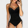 FJØRNA women's halter neck swimsuit with sweetheart bodice and ruched sides, shown on a model in a beach setting.