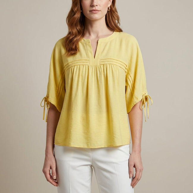 Yellow linen summer blouse for women by FJØRNA, flowing and lightweight, shown on a model with short sleeves and relaxed fit.