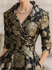 FJØRNA black and gold floral jacquard midi dress with a fitted waist and elegant design, perfect for formal occasions.