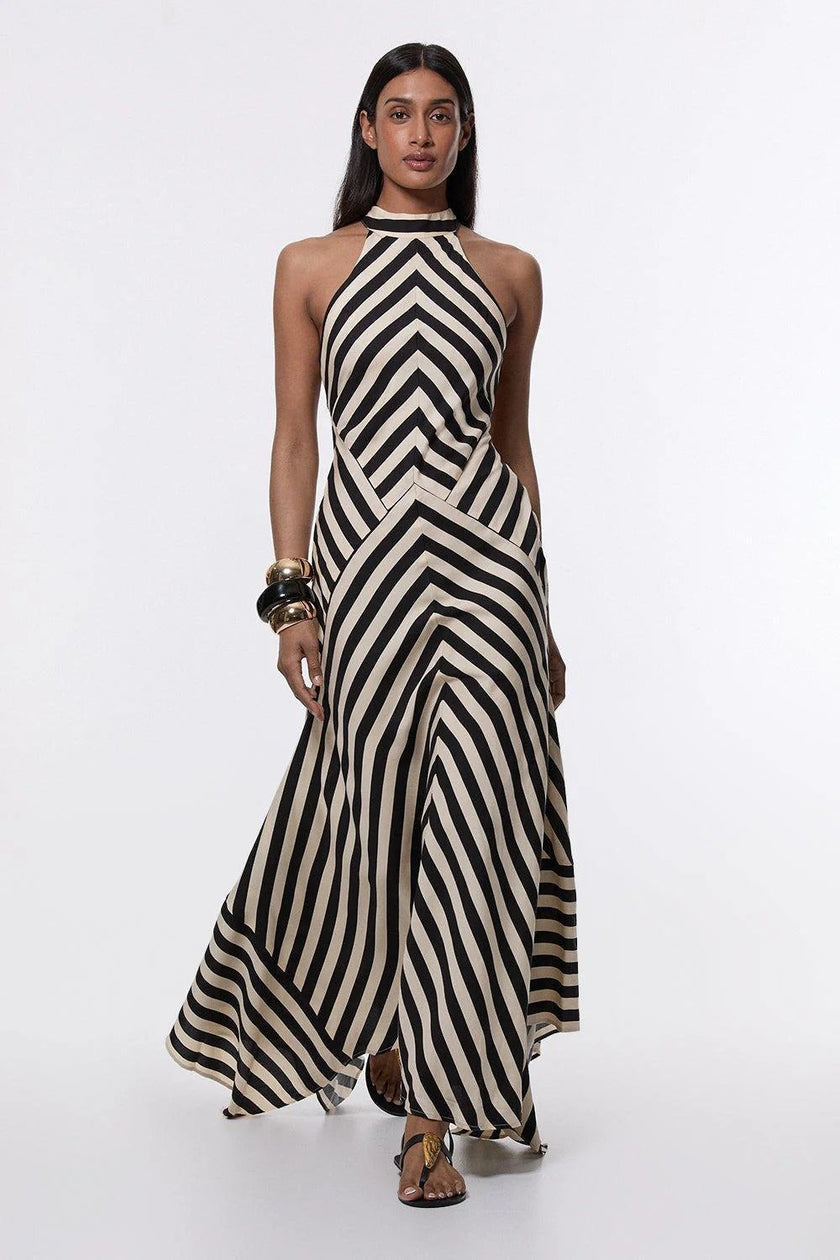 FJØRNA Mono Fluid Stripe Maxi Halter Dress in white, flowing fabric, sleeveless design, and elegant halter neckline.