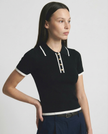 Black cotton polo top for women by FJØRNA, featuring a classic polo shirt design and a comfortable fit.