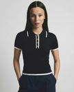 Black cotton polo top for women by FJØRNA, featuring a classic polo shirt design with a collar and short sleeves.