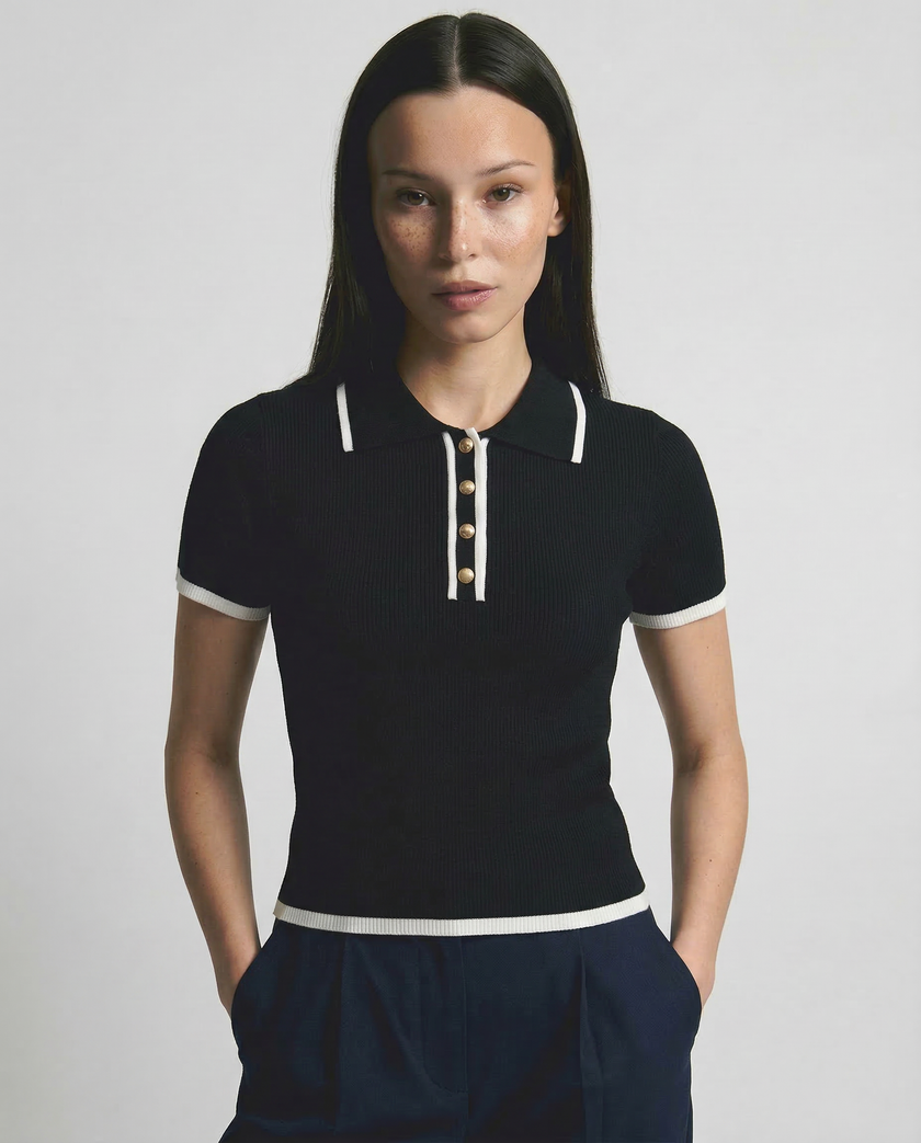 Black cotton polo top for women by FJØRNA, featuring a classic polo shirt design with a collar and short sleeves.