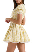 FJØRNA Emily Floral V-neck Corset Mini Dress in white with yellow floral pattern, sleeveless design, fitted silhouette, and mini length.
