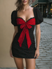 FJØRNA bold red bow polka dot mini dress showing a fitted sleeveless design with a bow detail at the waist and playful polka dots.