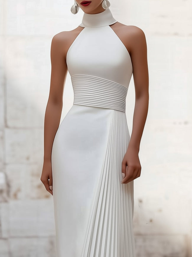 White satin pleated halter evening gown by FJØRNA with elegant design, showcasing the flowing pleats and sophisticated halter neckline.