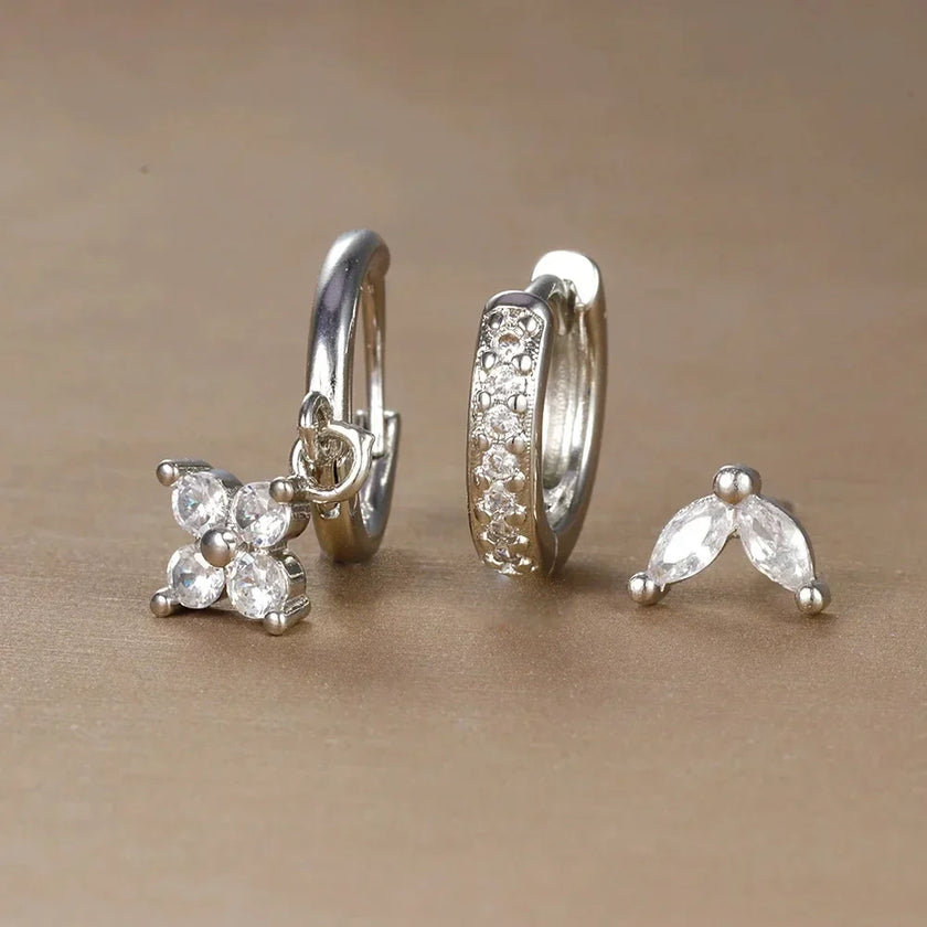 FJØRNA unisex minimalist piercing set with stainless steel hoops and studs, featuring gold and green hazel accents.