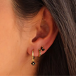 Unisex minimalist piercing set by FJØRNA featuring stainless steel hoops and studs with gold and green accents.