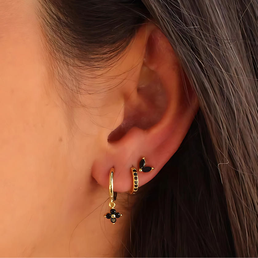 Unisex minimalist piercing set by FJØRNA featuring stainless steel hoops and studs with gold and green accents.