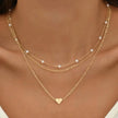 Gold 3-layer pearl pendant necklace set for women by FJØRNA, featuring layered gold and silver necklaces with heart and cross pendants.