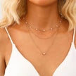 Gold 3-layer pearl pendant necklace set for women by FJØRNA, featuring layered gold and silver necklaces with heart and cross pendants.
