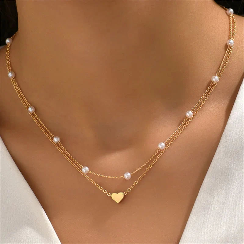 FJØRNA gold 3-layer pearl pendant necklace set featuring heart and cross charms, layered accessory for women.