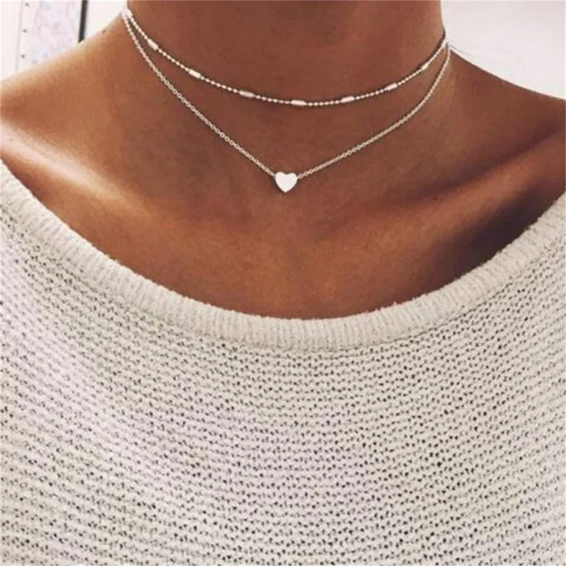FJØRNA gold 3-layer pearl pendant necklace set for women with heart and cross charms, layered design, gold and silver accents.