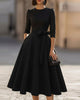 FJØRNA crew-neck A-line midi dress, elegant wedding guest dress in soft fabric, shown on a model with floral background.