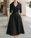 Black satin trench-collar wrap midi dress by FJØRNA, featuring a sleek design for elegant women’s occasion wear.