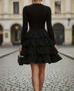 FJØRNA high-neck long-sleeve tiered ruffle mini cocktail dress shown on a model, featuring a stylish, layered design with ruffle details.